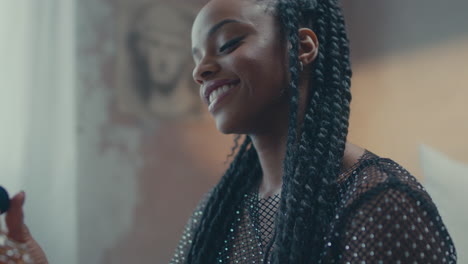 Happy-African-woman-applying-perfume-on-her-neck