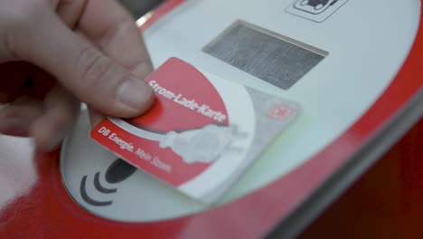 Close-up-of-a-hand-swiping-a-red-card-on-an-electronic-reader,-payment-or-access-concept,-blurred-background