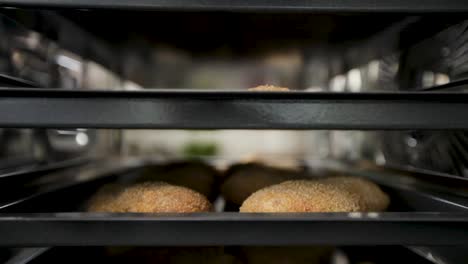 Frisch-Gebackene-Brotlaibe-Auf-Tabletts-In-Einer-Bäckerei,-Nahaufnahme,-Selektiver-Fokus