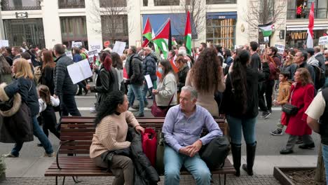 Käufer-Sitzen-Auf-Einer-Bank,-Während-Demonstranten-Ihre-Solidarität-Mit-Palästina-Bekunden