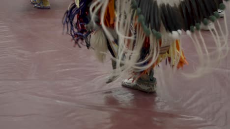 Intricate-footwork-of-dancers-adorned-in-elaborate-traditional-attire-at-Haskell-Indian-Nations-University's-Powwow-in-Lawrence,-KS