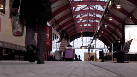 Travellers-with-luggage-on-platform-walk-next-to-train,-Malmö-Central-Station