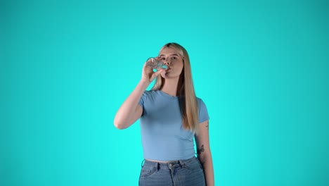 Happy-caucasian-woman-drinks-refreshing-water-out-of-glass-bottle,-turquoise