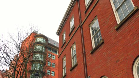 Red-brick-buildings-with-modern-glass-facade,-Manchester,-overcast-day,-urban-environment