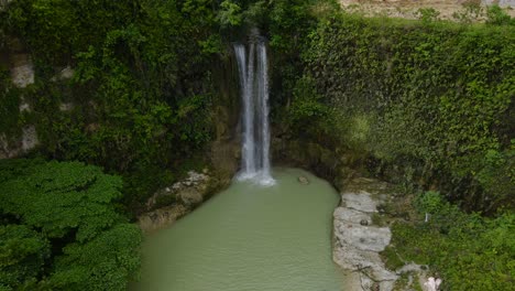 Lush-Camugao-Falls-cascading-into-a-serene-pool-surrounded-by-tropical-greenery,-Philippines,-tranquil-nature-scene