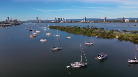 Aerial-views-moving-right-to-left-looking-towards-Surfers-Paradise,-over-yachts-on-anchor-and-the-Broadwater-on-the-Gold-Coast,-Australia