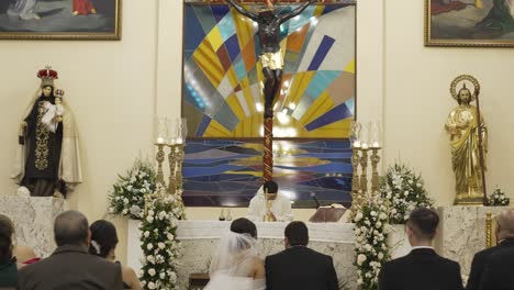 A-man-and-a-woman-get-married-in-a-Catholic-church-decorated-with-flowers-and-candles