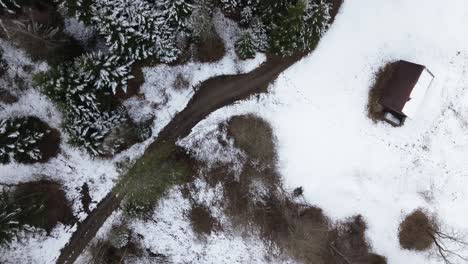 Aerial-4k-top-down-shot-of-small-house-next-to-road-in-beautiful-winter-mountain-landscape