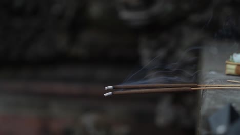 Two-incense-sticks-burning-with-smoke-rising-against-a-blurred-background-with-a-sense-of-calm-and-spirituality