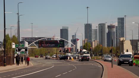 Stadtverkehr-In-Manchester-Mit-Fußgängern-Und-Moderner-Skyline-Im-Hintergrund,-Klarer-Tag