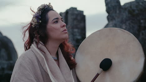 Mujer-Espiritual-Tocando-Un-Tambor-Chamánico-En-Una-Hermosa-Con-Una-Antigua-Torre-Medieval-Detrás-De-Su-Primer-Plano