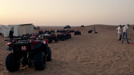 Quad-bikes-lined-up-on-Dubai-desert-sands-at-dusk,-ready-for-an-adventure-tour