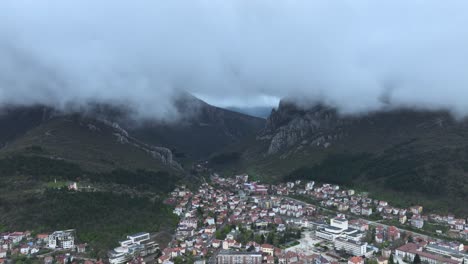 Toma-De-Ariel-De-Un-Pequeño-Pueblo,-Una-Montaña-Y-Nubes.