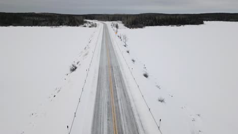A-White-Offroad-Pickup-Truck-Car-Driving-Under-Static-Drone-Shot-on-a-Winter-Snow-Covered-Highway-Road
