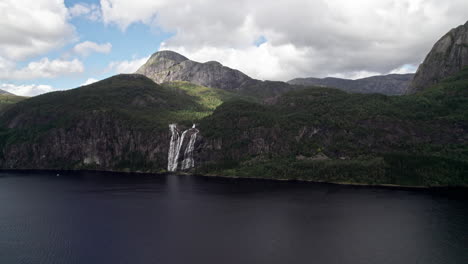 Aerial-shot,-panning-wide-around-a-tall-waterfall,-Laukelandsfossen,-in-Norway