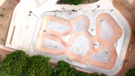 Top-down-shot-overhead-people-skating-on-half-pipes-within-a-skatepark