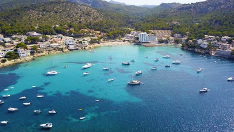 Playa-de-san-telmo-beach,-with-boats-and-clear-turquoise-waters,-aerial-view,-on-the-island-of-Mallorca,-Spain,-in-the-Mediterranean-Sea