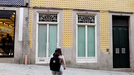 Woman-strolling-by-the-colorful-tiled-facades-in-Porto-city-center,-taking-a-photo