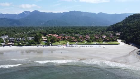 Alejamiento-Con-Drone-En-Una-Playa-Desierta-En-La-Costa-Norte-De-São-Paulo,-Cocoteros-Y-Vegetación-Al-Fondo