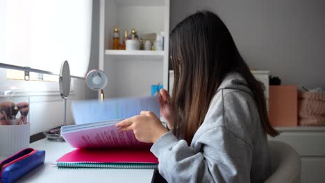 Young-Woman-reading-from-a-binder-at-a-study-desk-in-home-settings,-4K