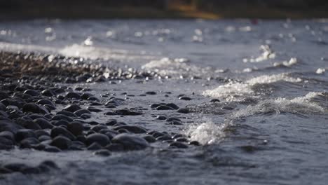 Waves-roll-and-crash-onto-the-shore-covered-with-dark-pebbles