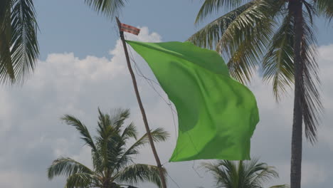 Green-flag-waving-over-Sandbank-Beach-on-Koh-Yao-Yai-Island,-Thailand---slow-motion