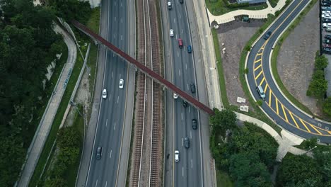 Toma-Aérea-De-Arriba-Hacia-Abajo-De-Una-Autopista-Muy-Transitada-En-Una-Ciudad-Americana,-Con-El-Horizonte-En-Segundo-Plano.