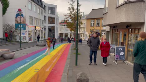 Pedestrians-walk-on-Rainbow-Street-in-Reykjavik,-Iceland-on-cloudy-day