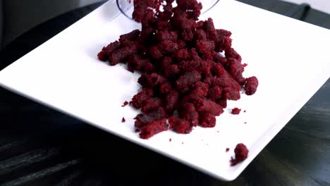 Adding-beet-pulp-muffin-pellets-into-a-white-plate-preparing-to-make-a-chocolate-beet-pulp-muffin