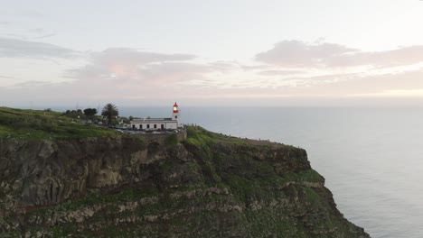 Toma-De-Drone-De-Un-Faro-En-Una-Colina-Y-Vista-Al-Mar.