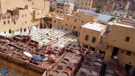 Fez,-Chouara-Tannery,-showing-the-leather-coloring-process-and-the-prefilled-leather-dyeing-pits-with-the-prepared-materials-in-Morocco