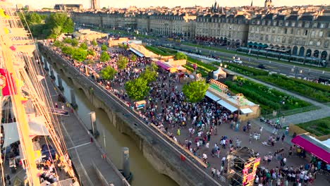 Sailing-ship-in-the-Garonne-River-during-Wine-Fair-with-large-crowds-near-shore,-Aerial-rising-shot