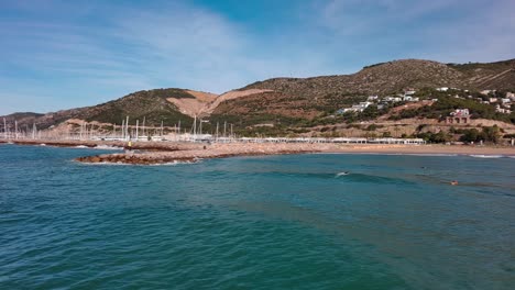 Coastal-marina-of-Port-Ginesta-in-Barcelona-with-boats-and-hills-under-blue-sky