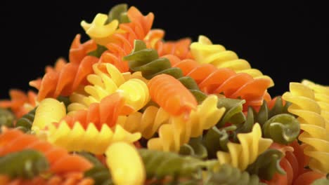 Close-up-macro-of-dry-spiral-pasta,-macaroni-rotating-on-a-black-background