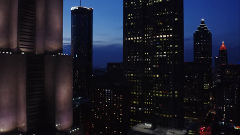 Drone-shot-of-Atlanta-Georgia-famous-skyscrapers-illuminated-with-night-light-under-twilight-sky,-USA