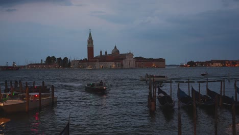 Scenic-view-of-Venice-at-dusk-from-pier-with-several-boats-and-gondolas,-Italy