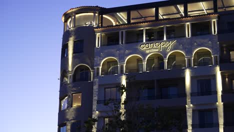 Canopy-Hotel-by-Hilton-lit-at-night-with-clear-sky,-Handheld-long-shot