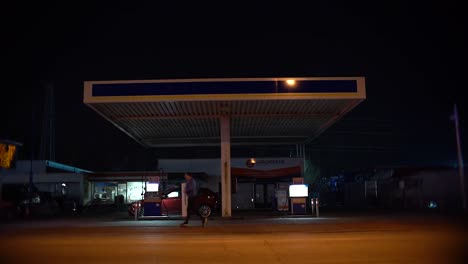 Toma-De-Gasolinera-Por-La-Noche-Con-Coche,-Bicicleta-Y-Corredor