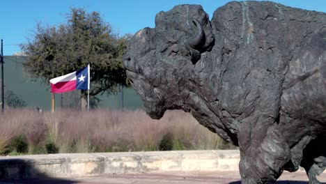 Buffalo-statue-and-Texas-state-flags-in-the-background-at-Frontier-Texas-in-Abilene,-Texas-and-stable-video-close-up