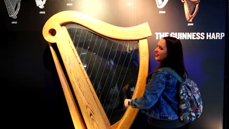 Sonrisas-De-Turistas-Tocando-El-Gran-Arpa-Guinness-En-Dublín,-Irlanda