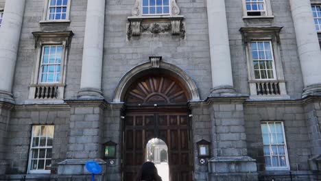 Female-tourist-entering-Trinity-College-in-Dublin,-Ireland