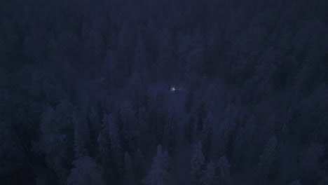 Ein-Skifahrer,-Der-Im-Dunkeln-Mitten-In-Einem-Verschneiten-Wald-Klettert,-Wobei-Die-Einzige-Lichtquelle-Eine-Stirnlampe-Ist.