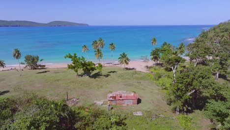 Beach-shack-on-remote-Caribbean-coastline-with-bright-blue-sea-water