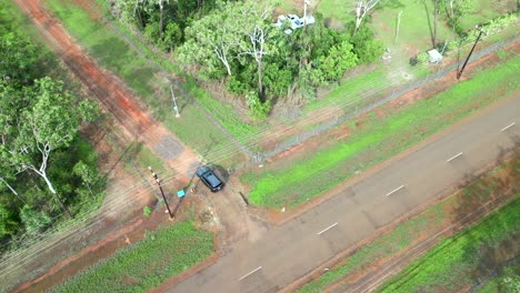 Aerial-drone-of-Car-Auto-Pulling-Into-Gravel-Dirt-Road-Driveway-To-House-In-Forest-Outback,-Tracking-Follow-Descend