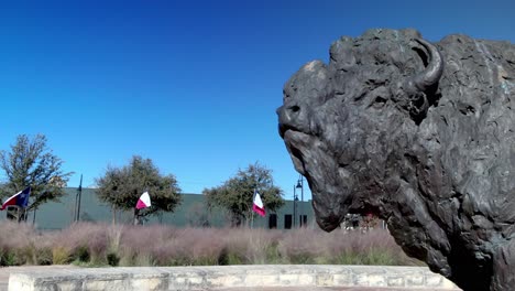 Buffalo-statue-and-Texas-state-flags-in-the-background-at-Frontier-Texas-in-Abilene,-Texas-and-stable-video