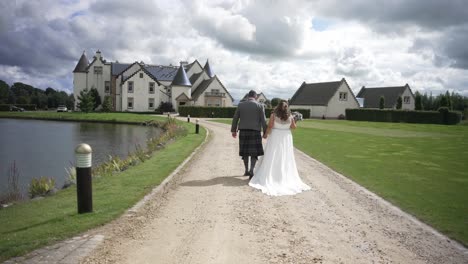 Newly-wedded-couple-stroll-hand-in-hand-towards-the-celebration-venue