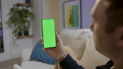 Detalle-De-Un-Hombre-Viendo-Un-Vídeo-En-Su-Teléfono-Celular-En-Casa---Pantalla-De-Teléfono-Celular-En-Clave-De-Croma-Verde-Para-Inserción-Gráfica