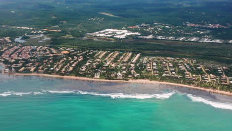 Aerial-view-of-Praia-do-Forte-beach,-the-city-around-and-the-vegetations-on-a-cloudy-day,-Praia-do-Forte,-Bahia,-Brazil
