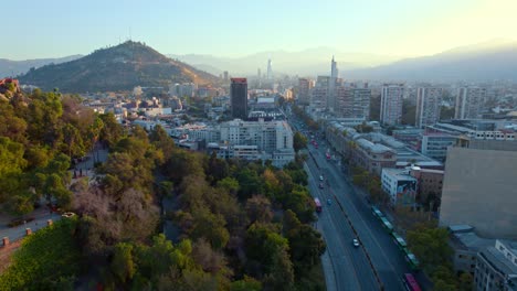 Alameda-street-in-santiago,-dawn-light-over-cityscape-with-andes-backdrop,-cultural-center-visible,-aerial-view