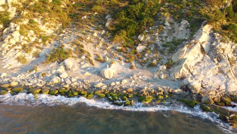 Golden-hour-sunlight-shines-on-rugged-rocky-coastline-of-Santa-Marta-Magdalena-Colombia-as-ocean-waves-crash-on-beach